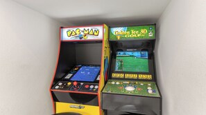 Zwei Spielautomaten, einer mit der Aufschrift 'PAC-MAN' und der andere mit 'Golden Tee 3D'.