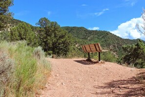 A dirt path leading to a wooden bench with a sign, surrounded by greenery and hills. - River View Ridge w/ Hot Tub/Dog Friendly (Glenwood Springs)