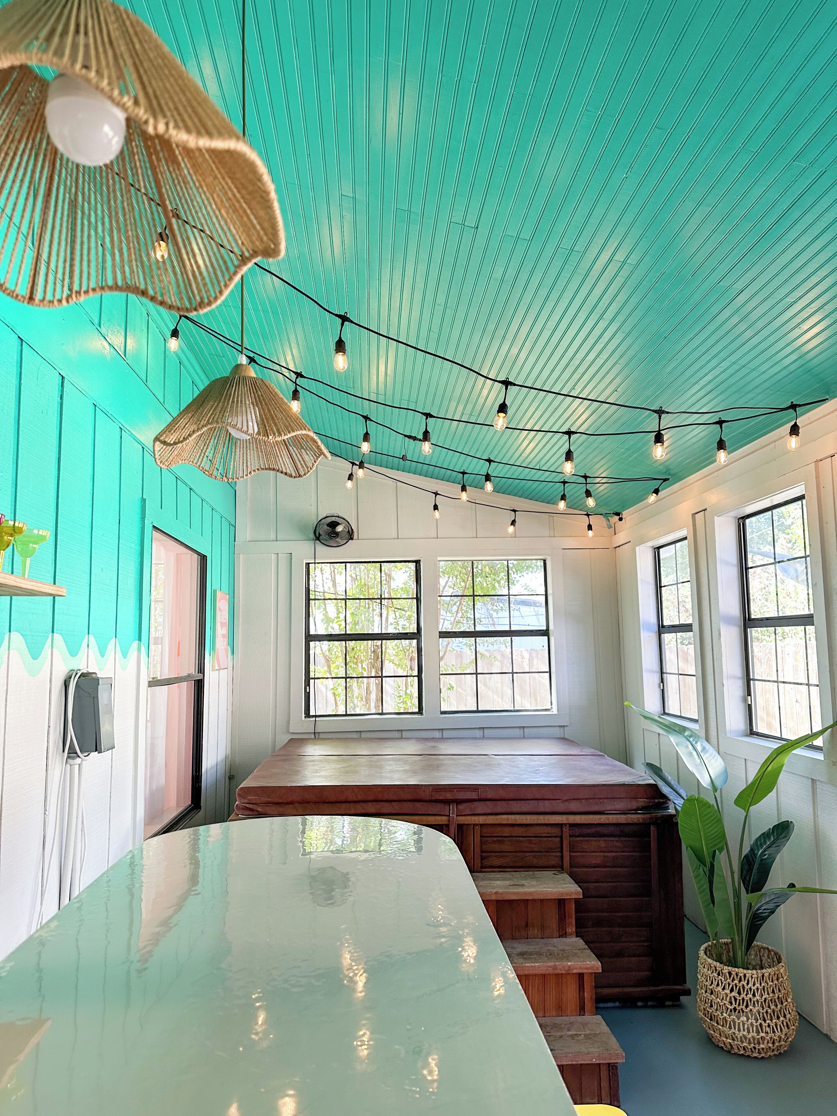 A room with a teal ceiling, a long wooden bench, and a large window.
