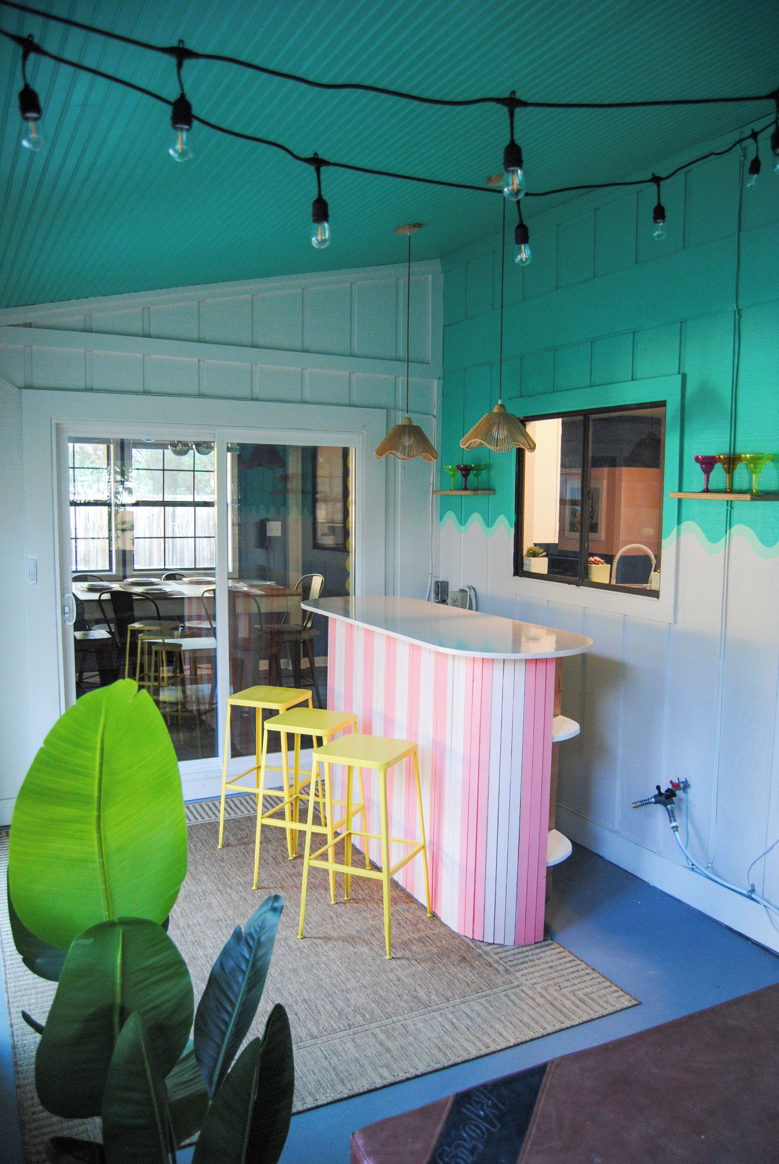 A kitchen with a bar area, bar stools, and a large plant.