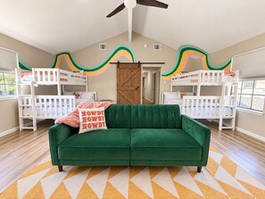 Ein Zimmer mit Etagenbetten, einem grünen Sofa und einem gemusterten Teppich.