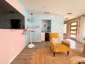 A room with a wooden floor, a yellow armchair, a horse sculpture, and a wall with horse patterns.