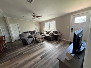 A living room with a ceiling fan, two couches, a coffee table, and a television. - Blue’s Oasis- less than 15 minutes from Rocker B Ranch (Graford)