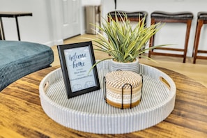 Un panneau d’accueil encadré, une plante en pot et un objet décoratif posés sur un plateau en bois rond.