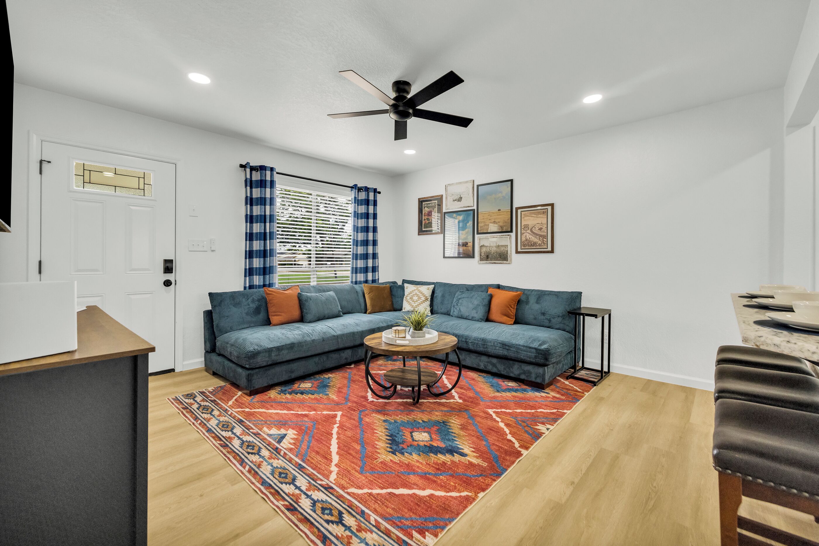 A living room with a sectional sofa, a coffee table, a patterned rug, and a ceiling fan.