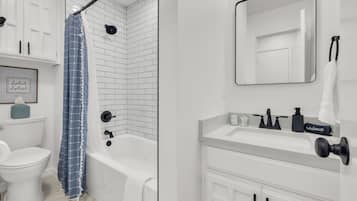 Een moderne badkamer met een wit toilet, een badkuip, een douche en een wastafel met een spiegel.