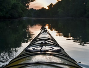 A kayak on a calm body of water with a forested shoreline in the background. - Hidden Oaks Resort - White Oak (Walling)