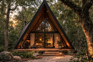 A modern, triangular wooden cabin with a glass front, surrounded by trees. - Hidden Oaks Resort - White Oak (Walling)