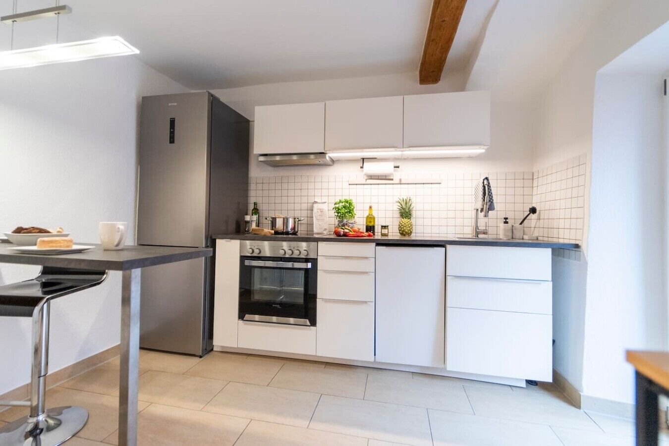 Eine moderne Küche mit weißen Schränken, Edelstahlgeräten und einer gefliesten Spritzschutzwand.