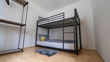 Ein Stockbett in einem Zimmer mit Holzboden und weißen Wänden.