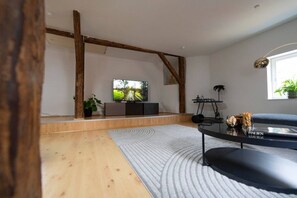 A modern living room with a flat-screen TV, wooden beams, a sofa, and a coffee table.