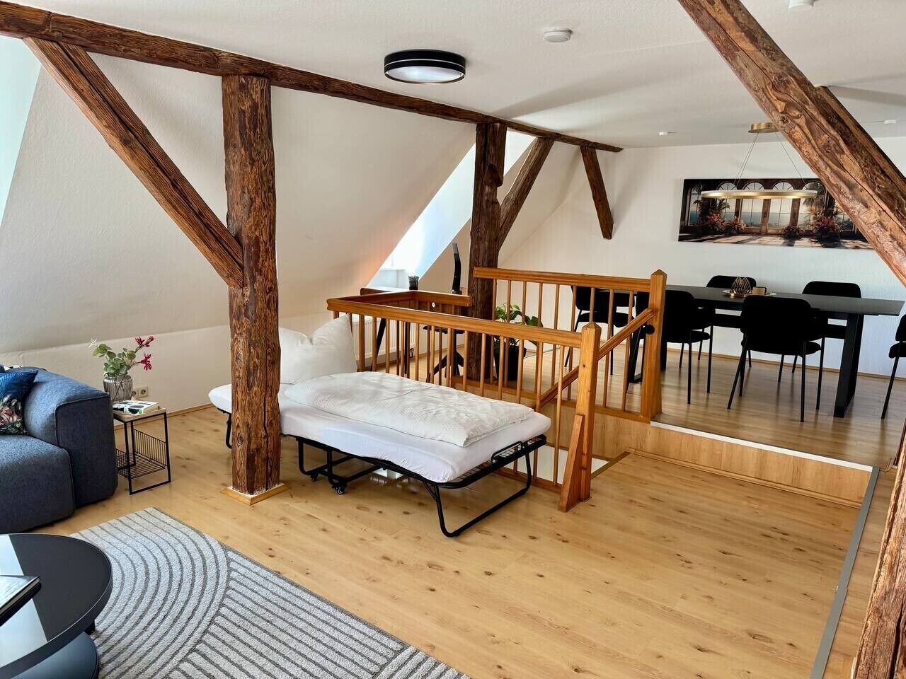 Ein Schlafzimmer im Loft-Stil mit Holzbalkendecke, einem Bett, einem Essbereich und Blick ins Freie.