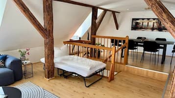 Ein Schlafzimmer im Loft-Stil mit Holzbalkendecke, einem Bett, einem Essbereich und Blick ins Freie.