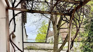 A covered outdoor seating area with a metal table and chairs, a potted plant, and a patterned rug. - "Ferro" – historical and modern, with a balcony (Günzburg)