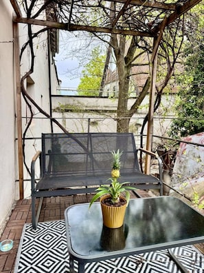 A covered outdoor seating area with a metal table and chairs, a potted plant, and a patterned rug. - "Ferro" – historical and modern, with a balcony (Günzburg)