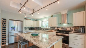 A modern kitchen with a central island, stainless steel appliances, and a wine rack. - Escape to your own private luxury estate in the heart of Sedona Wine Country. Designed for groups of up to 14 guests, The Reserve offers a rare combination of relaxation, connection, and adventure. Enjoy pickleball matches, evening hot tub gatherings (Cornville)
