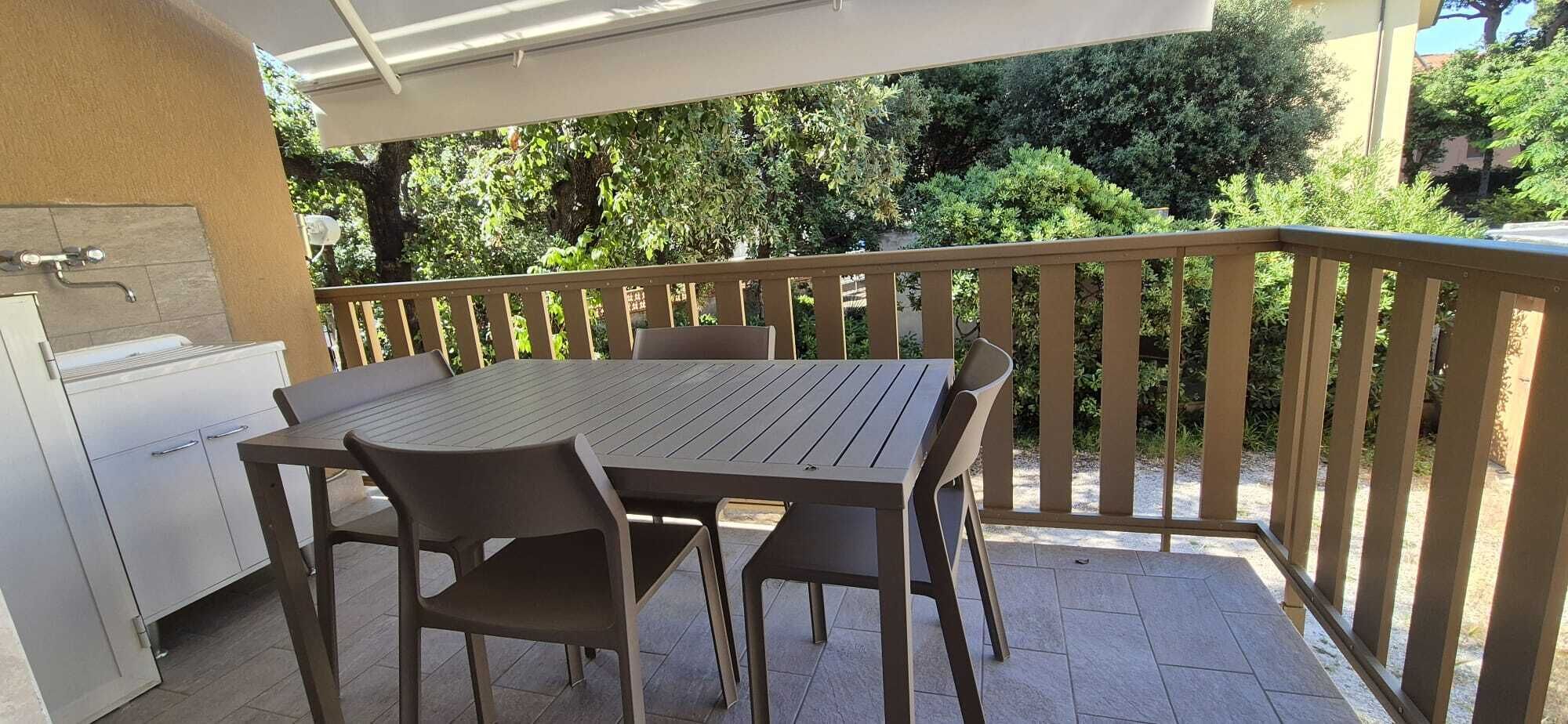 An outdoor patio with a table and chairs, a barbecue grill, and a covered area.