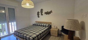 A bedroom with a bed, bedside table, lamp, and wall art. - TIRRENO APARTMENT, NEW, TERRACE, PARKING SPACE, AIR CONDITIONING, INTERNET, 100 M FROM THE BEACH (San Vincenzo)