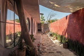 Un patio con sendero empedrado, plantas en macetas y una zona de estar.