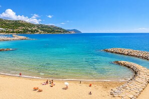 A beach with clear turquoise water, a stone jetty, and orange beach chairs. - La Loggia sul Mare, a beachfront apartment just a few steps from the beach. (San Lorenzo al mare)