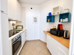 A compact kitchen with white cabinets, a built-in oven, a microwave, and a coffee machine on the countertop. - La Loggia sul Mare, a beachfront apartment just a few steps from the beaches. (San Lorenzo al mare)