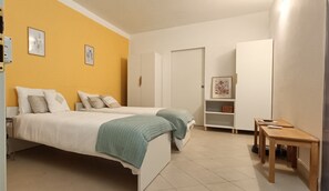 A bedroom with two beds, a wardrobe, a small table, and a shelf with a framed picture. - La Loggia sul Mare, a beachfront apartment just a few steps from the beaches. (San Lorenzo al mare)