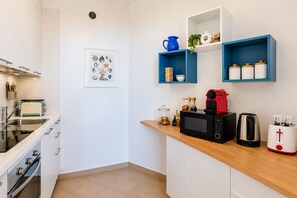 Eine moderne Küche mit weißen Schränken, einer Holzarbeitsplatte, einem Toaster, einem Wasserkocher und einer Kaffeemaschine.