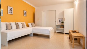Ein modernes Schlafzimmer mit einer weißen Couch, einem kleinen Holztisch und einem weißen Kleiderschrank.