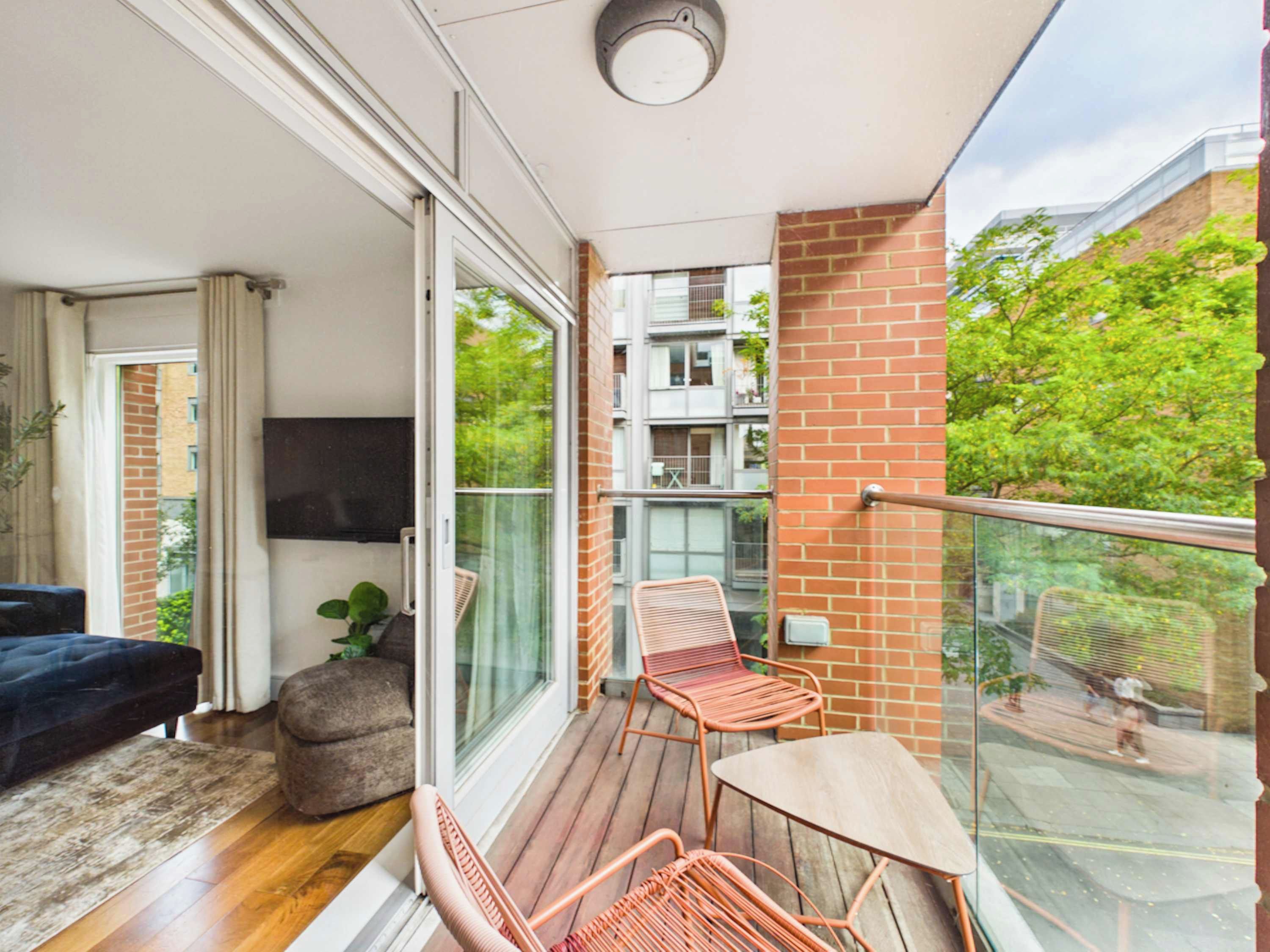 A balcony with a glass door, a sofa, a table, and chairs.