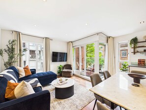 Een moderne woonkamer met een bank, salontafel en eettafel.
