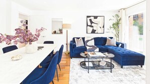 A modern living room with a dining area, featuring a sofa set, a coffee table, and a dining table with chairs. - Westminster Spacious 2BR Apartment with Balcony (Greater London)