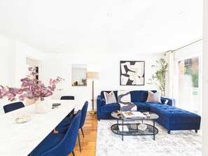 A modern living room with a dining area, featuring a sofa set, a coffee table, and a dining table with chairs. - Westminster Spacious 2BR Apartment with Balcony (Greater London)
