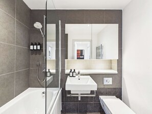 A modern bathroom with a glass-enclosed shower, a white sink, and a bathtub. - Westminster Spacious 2BR Apartment with Balcony (Greater London)