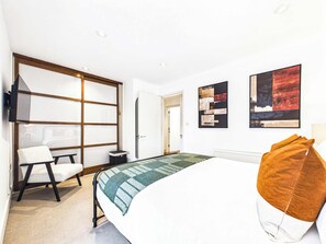 Ein Hotelzimmer mit Bett, Schreibtisch, Stuhl, Heizkörper und Bildern an den Wänden.