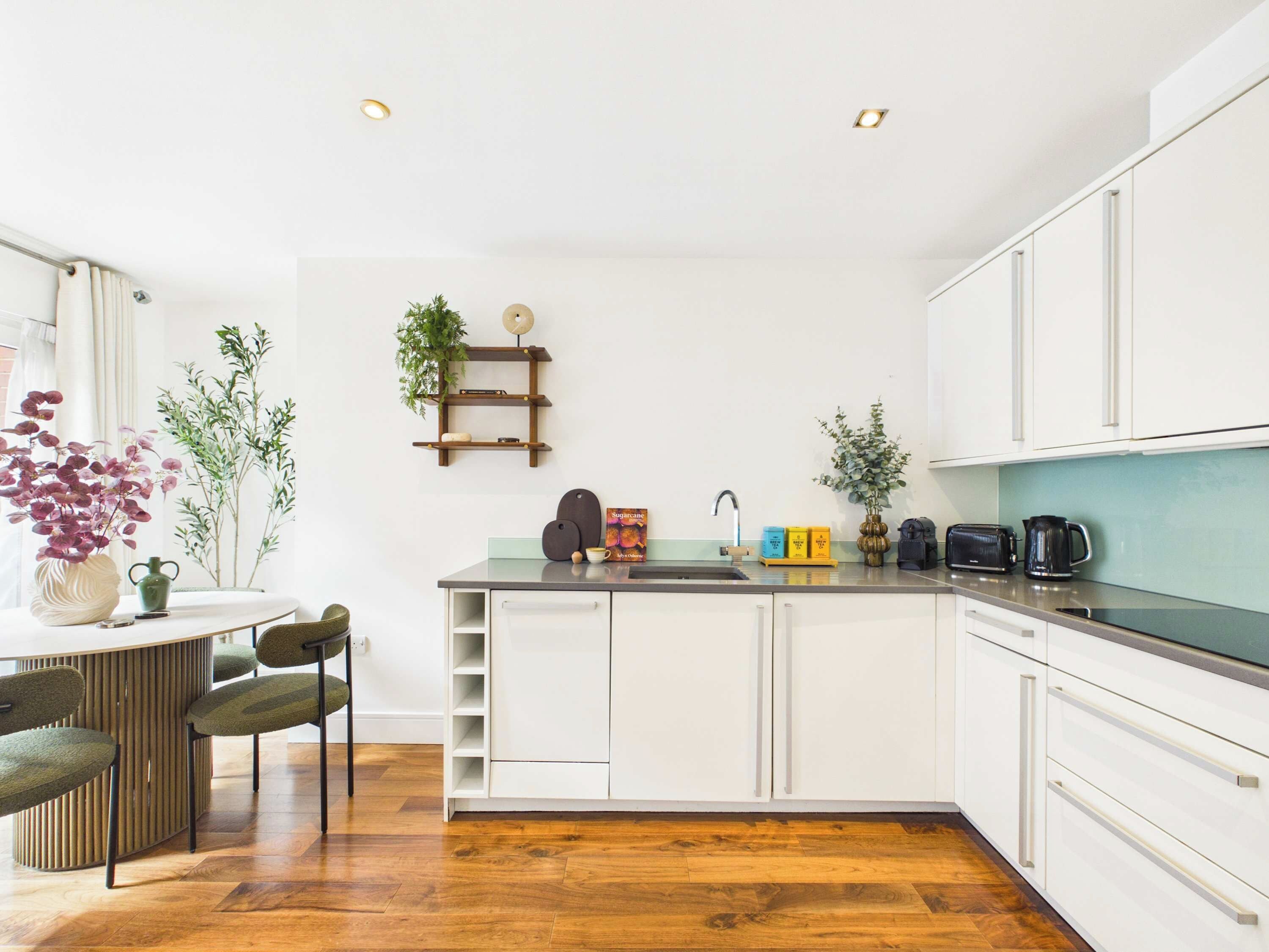 A modern kitchen with white cabinets, a wooden countertop, and a built-in sink.