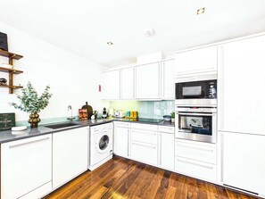 Eine moderne Küche mit weißen Schränken, einer Waschmaschine, einer Mikrowelle und einem Toaster.
