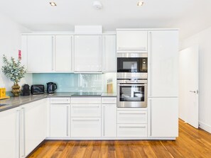 Una cocina moderna con armarios blancos, horno integrado y microondas.