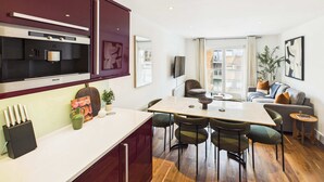 A modern kitchen with a dining area, featuring a large island, chairs, and a view to the outside. - Spacious and Bright Westminster Apartment (Greater London)