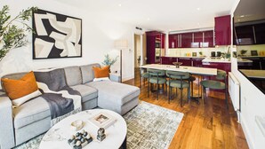 A modern living room with a grey sofa, a coffee table with decorative items, and a large abstract painting on the wall. - Spacious and Bright Westminster Apartment (Greater London)