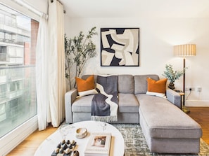Ein modernes Wohnzimmer mit einer grauen Eckcouch, einem runden Couchtisch und einem großen abstrakten Gemälde.
