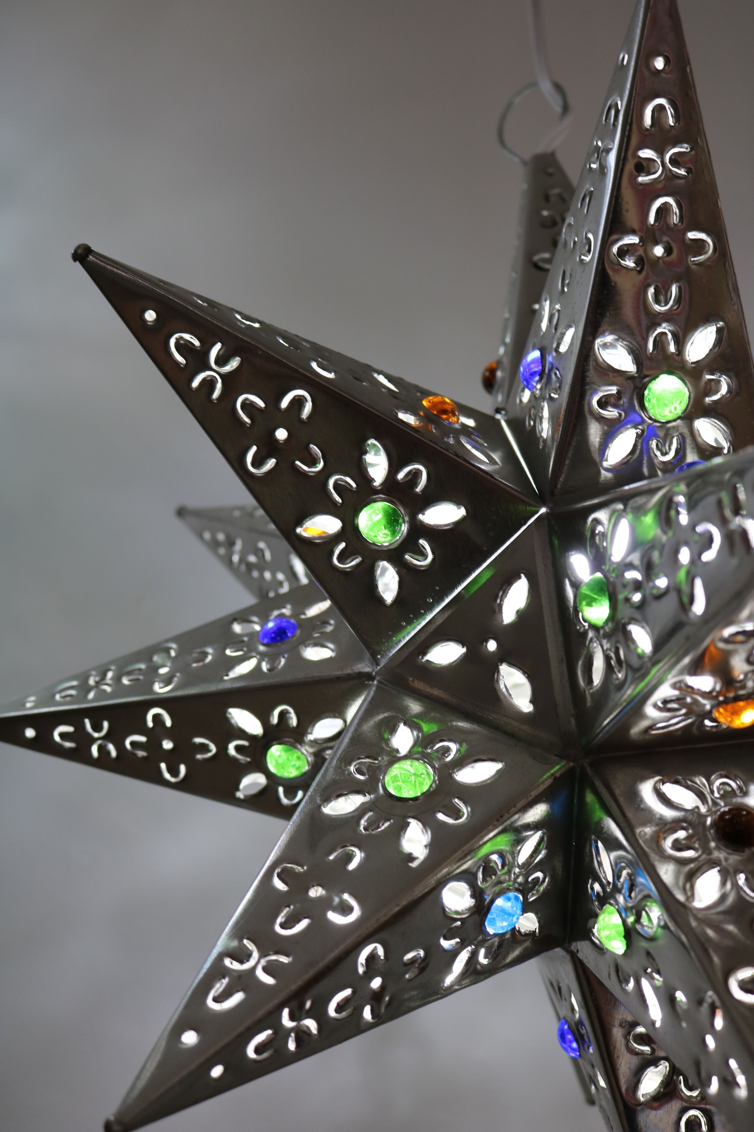 Una lámpara metálica con forma de estrella, con varios orificios y luces de colores incrustadas.