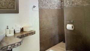Kylpyhuone, jossa on kiviseinä, wc-istuin, marmoritasoinen pesuallas ja pyyheteline.