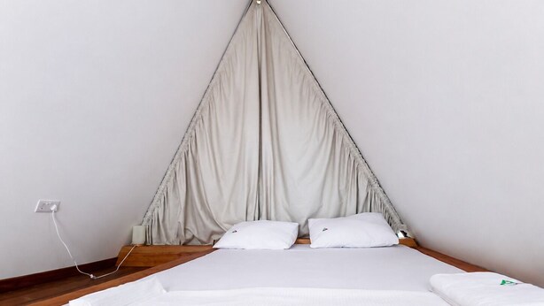 A single bed with a canopy, white bedding, and a power outlet on the wall. - EVERGREEN VILLA (Dar es Salaam)