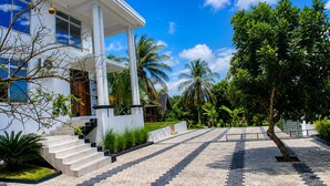 A modern building with a white facade, large windows, and a prominent red spherical object on the roof. - EVERGREEN VILLA (Dar es Salaam)