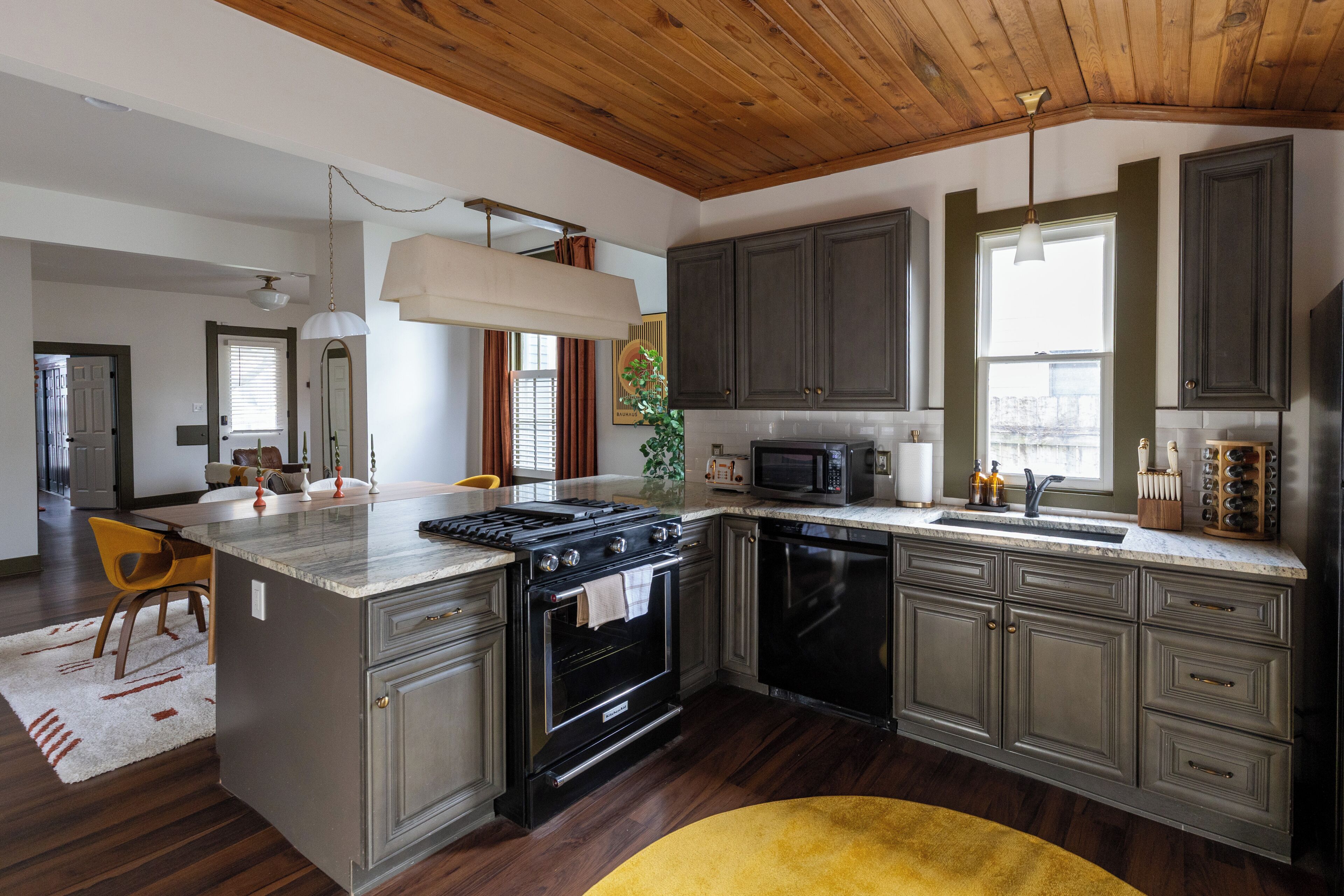 Una cocina moderna con una isla central, muebles oscuros y una campana extractora de acero inoxidable.
