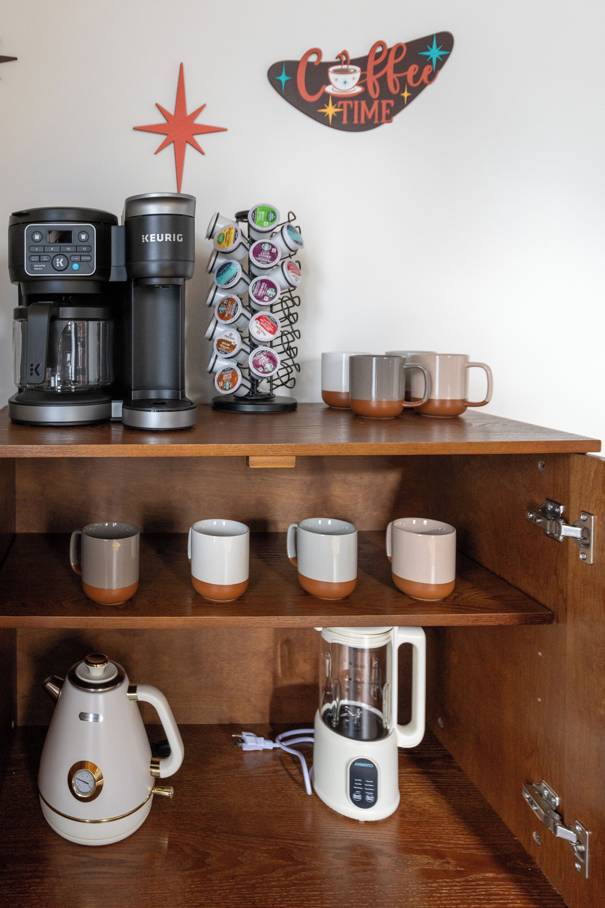 A coffee station with a Keurig coffee maker, a coffee mug rack, and a coffee pot.