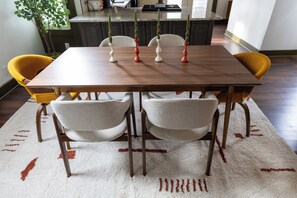 A dining table with four chairs, a patterned rug, and a kitchen in the background. - Walk to Mass Ave , Charming 3BR with 2 Kings, Garage & fire pit (Indianapolis)