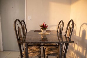 Una mesa de comedor con cuatro sillas, una planta pequeña en maceta y un felpudo.