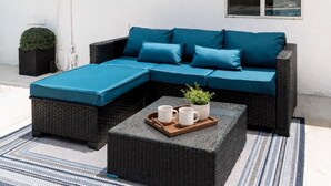 Un canapé modulable avec des coussins bleus, un pouf assorti et un plateau avec des tasses et une plante.