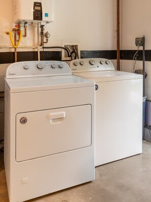 Ein Waschraum mit zwei Whirlpool Waschmaschinen und Trocknern, einem Warmwasserbereiter und einer Steuerungseinheit.